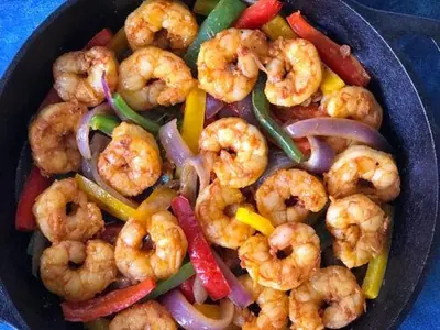 Sautéed shrimp with peppers and onions in a serving skillet