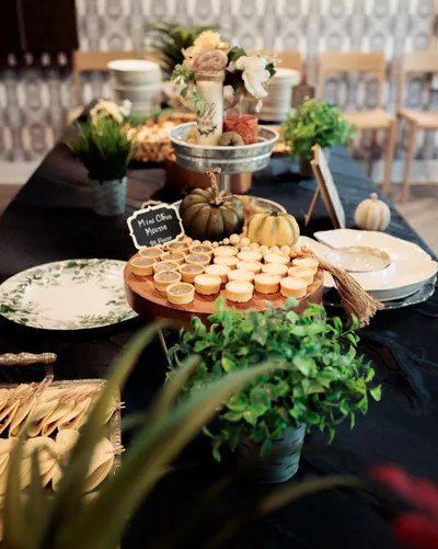 Mini citrus mousse cups on a wooden stand among pumpkins and potted greenery