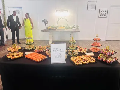 Couple beside a reception table of pinwheels, salmon rolls and tiered appetizers