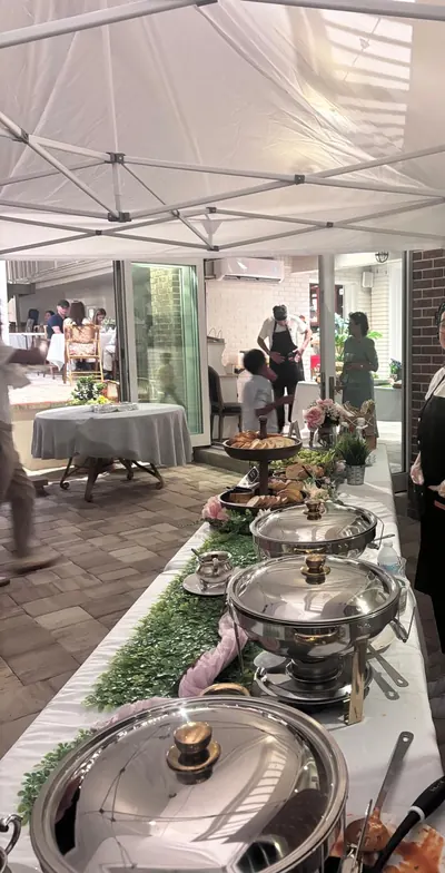 Buffet line of chafing dishes laid with greenery under a white tent