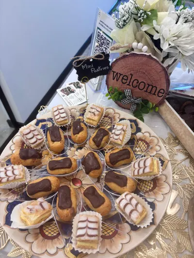 Mini éclairs and pastries on a painted platter beside a welcome sign